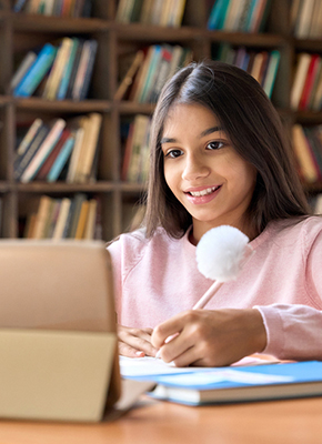 A girl smiling while using a laptop to complete her lessons